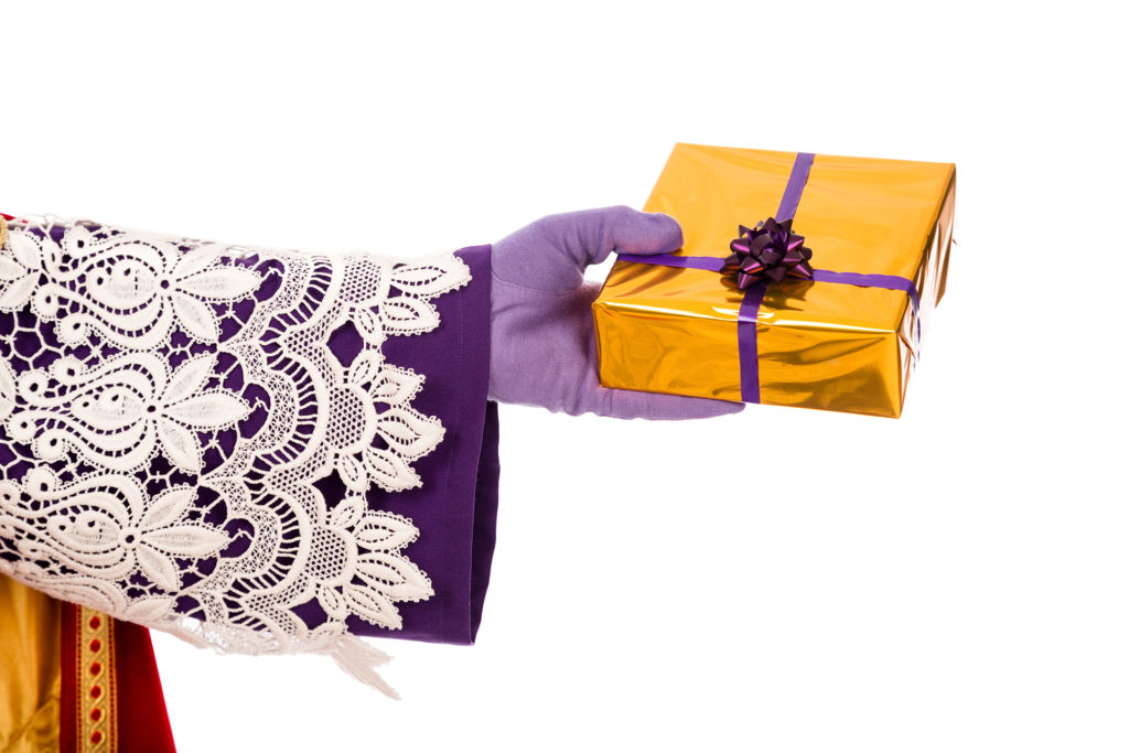 Hand of Sinterklaas showing gift. Isolated Hand of sinterklaas with gift . typical Dutch character part of a traditional event celebrating the birthday of Sinterklaas (Santa Claus) in december.